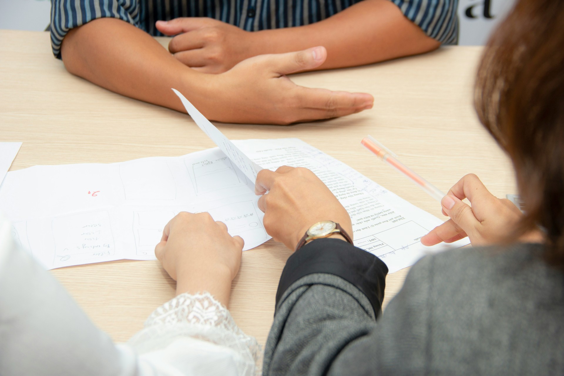 Hands discussing documents on table